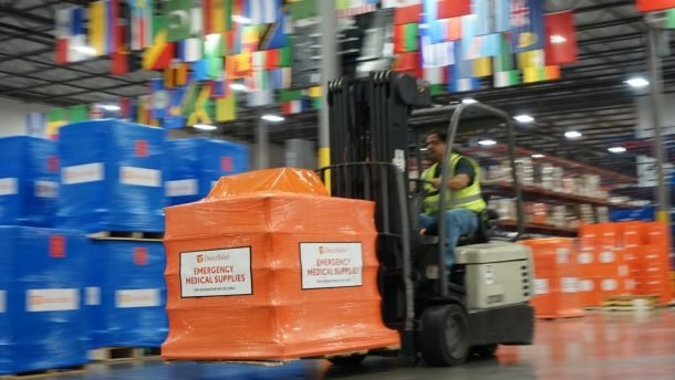 A forklift moving an orange pallet of medical aid in Direct Relief's warehouse