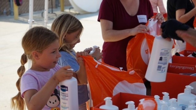 People volunteer with Direct Relief, packing supplies into orange bags